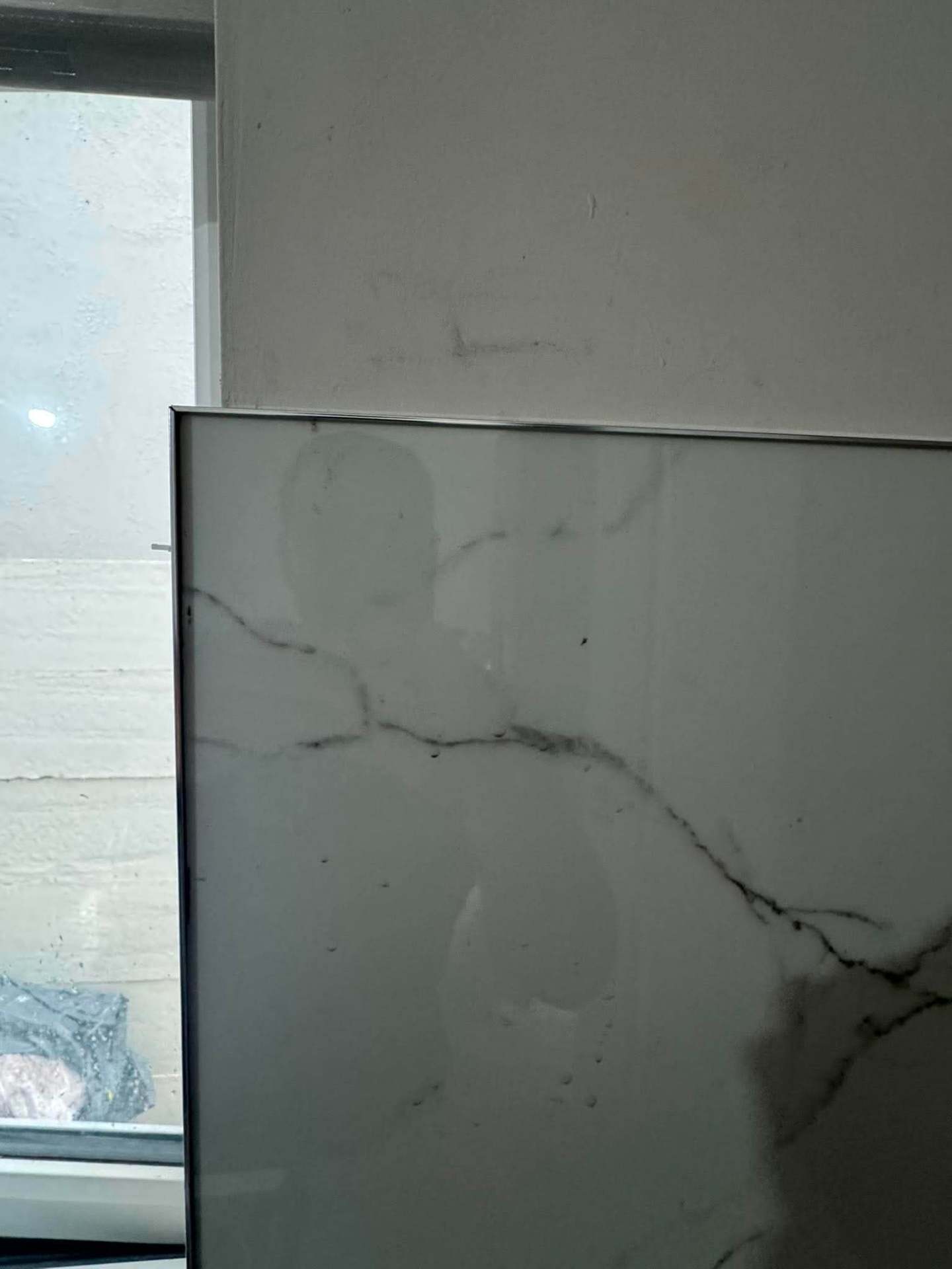 Large-format Calacatta porcelain kitchen splashback panel set against window reveal