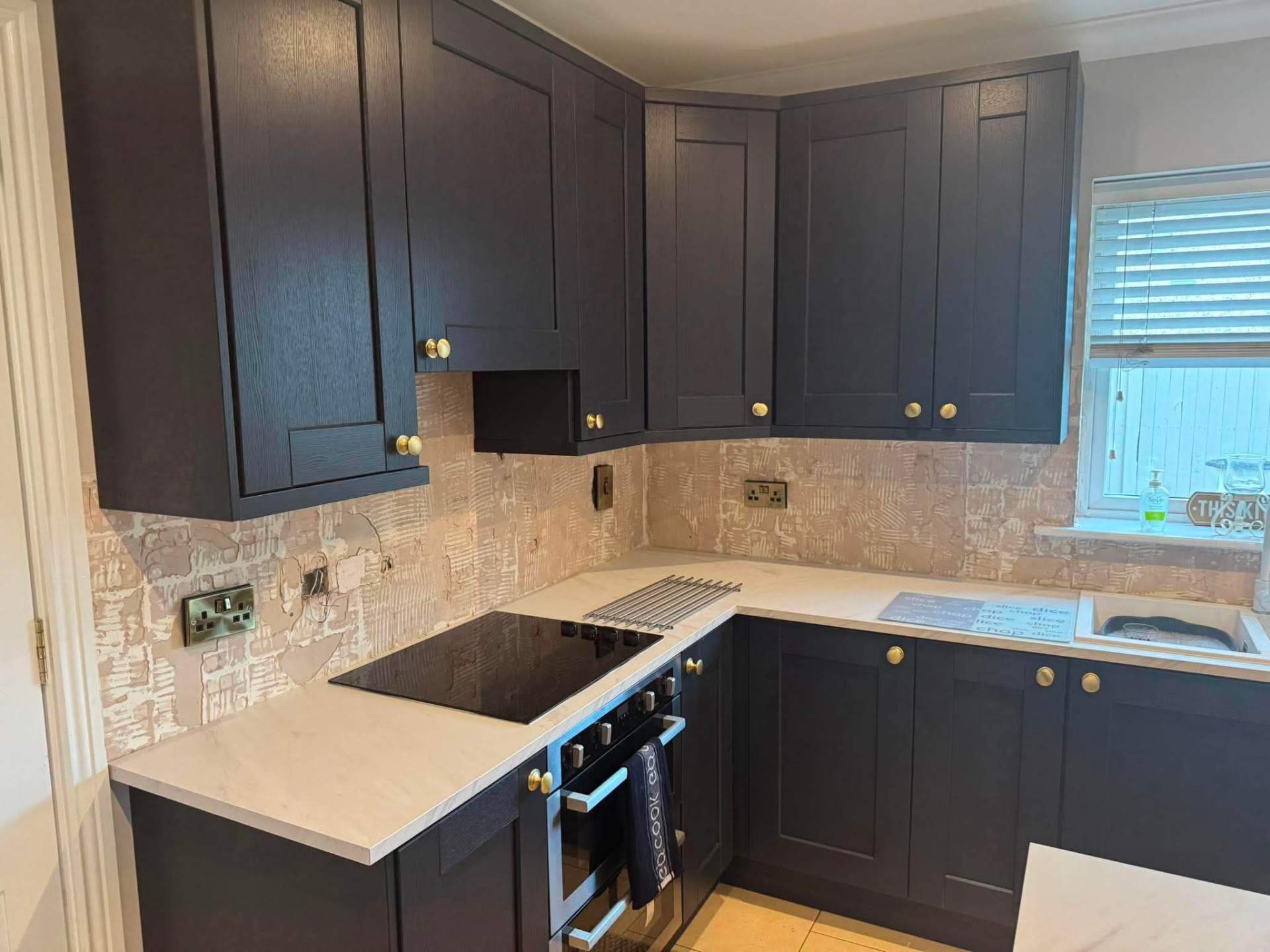 Navy shaker kitchen finished with stone-effect splashback