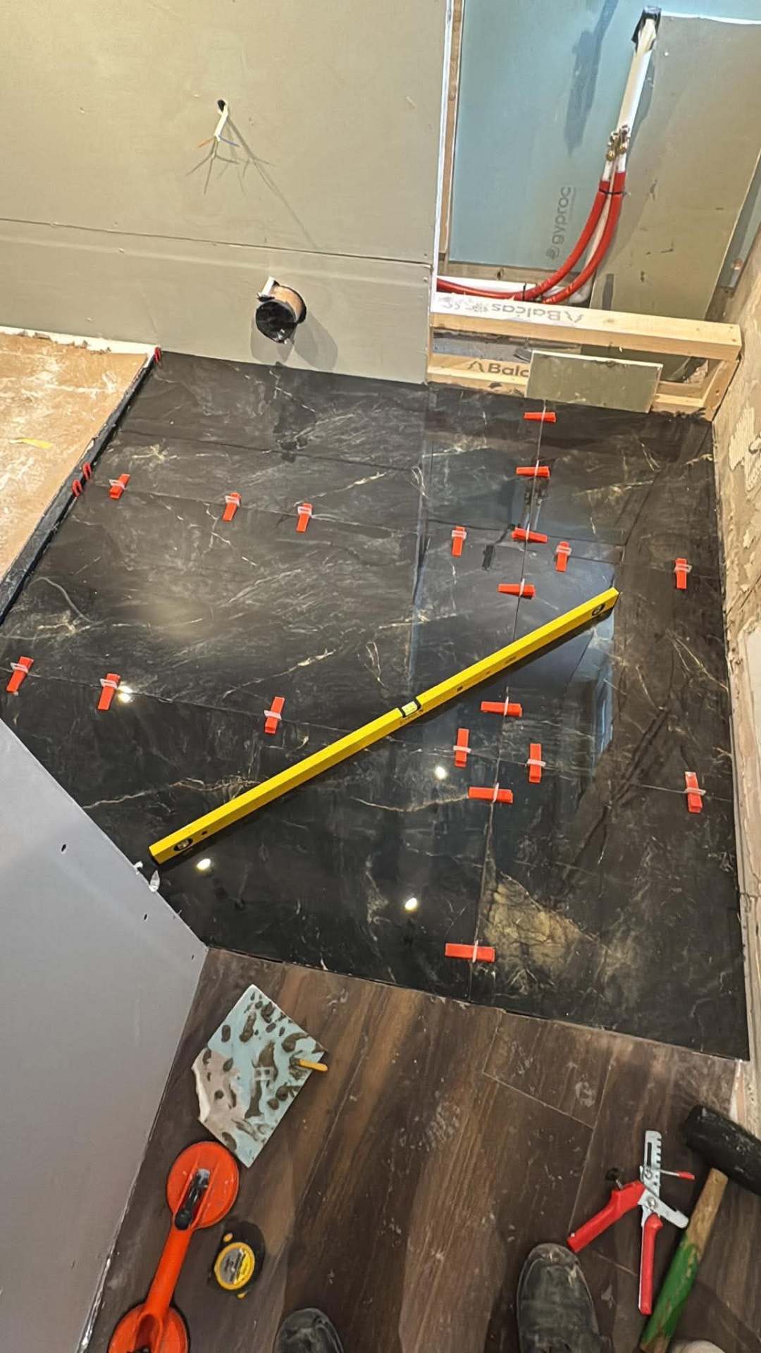 Dark marble wall — levelling clips holding tiles flush