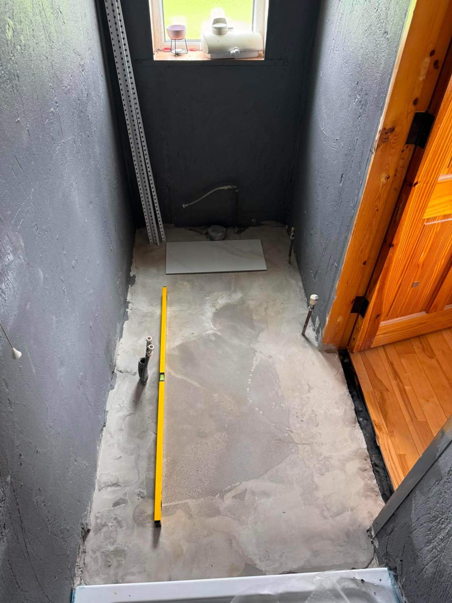 Small bathroom stripped to bare floor before tile