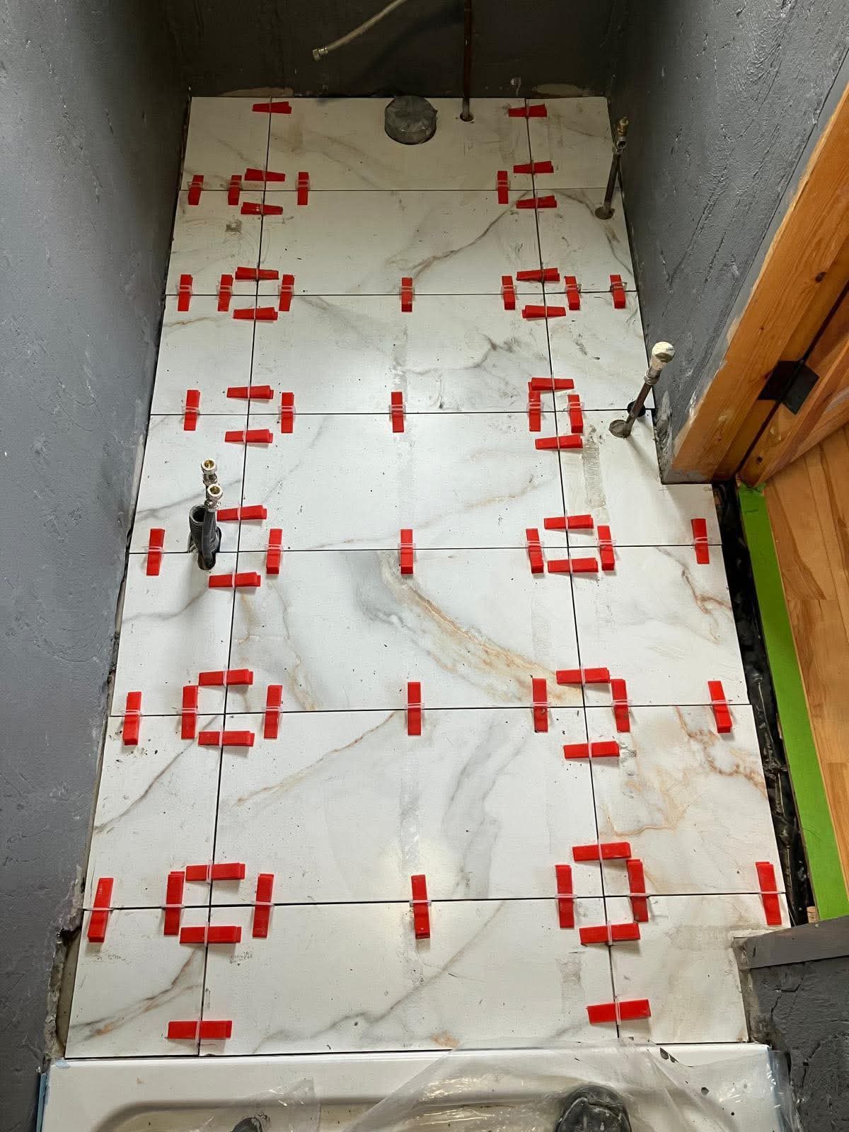 Calacatta marble bath surround with red levelling clips