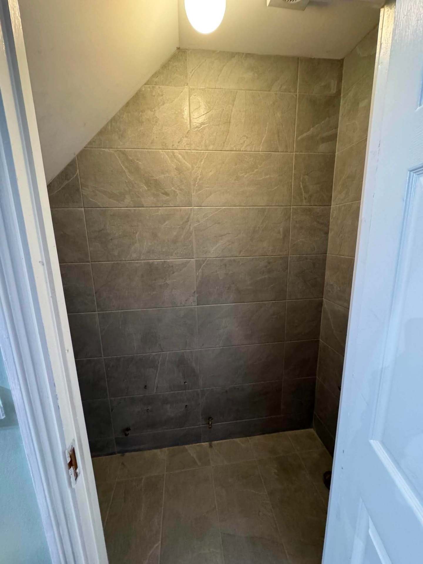 Under-stairs WC — slate-effect walls and door reveal