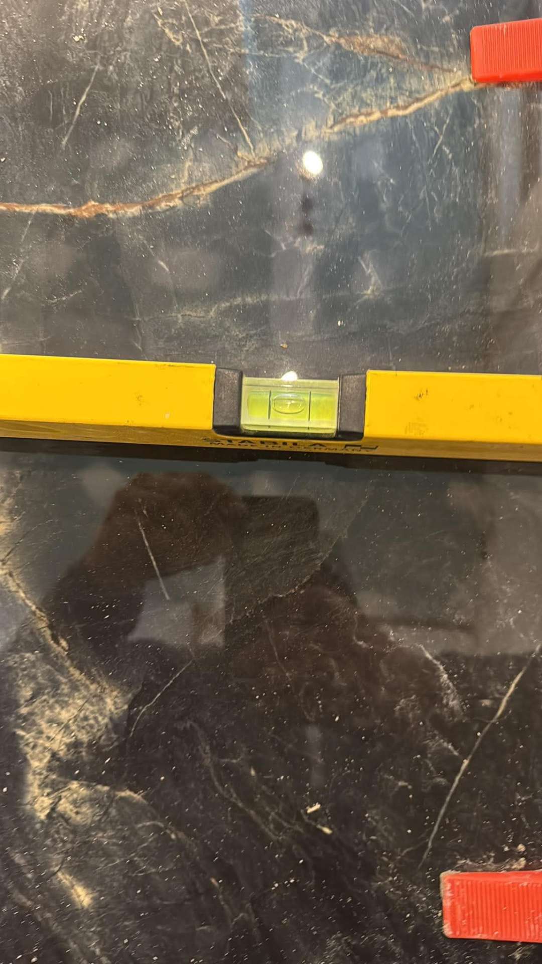 Dark marble feature wall during setting out, yellow level on the tile